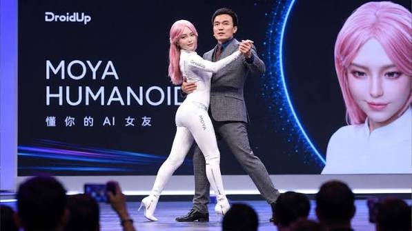 MOYA humanoid on stage with a presenter at the DroidUp reveal